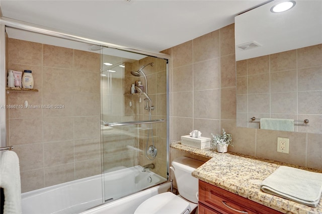 full bathroom with toilet, enclosed tub / shower combo, vanity, and tile walls