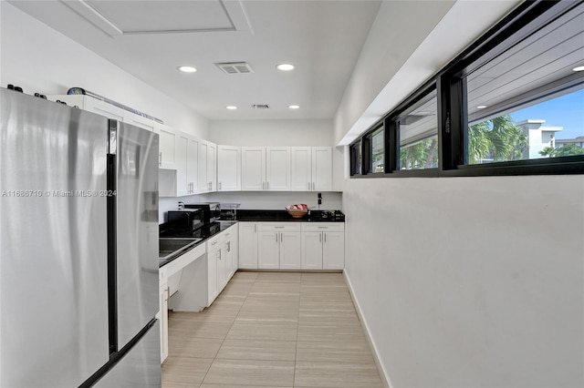 kitchen featuring stainless steel refrigerator, light tile patterned flooring, and white cabinets