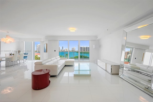 tiled living room featuring a wealth of natural light, a water view, and a chandelier