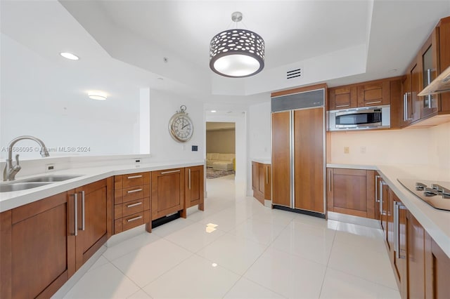 kitchen with built in appliances, hanging light fixtures, sink, and light tile patterned floors