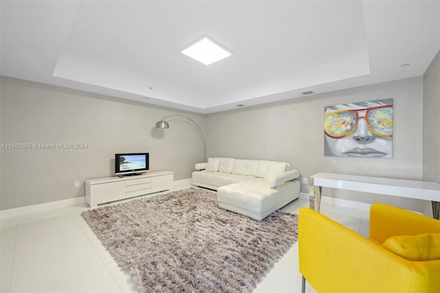 living room with light tile patterned floors and a tray ceiling