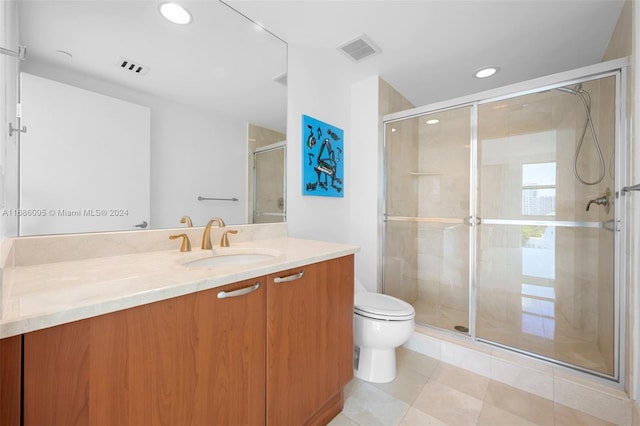 bathroom with a shower with shower door, vanity, toilet, and tile patterned flooring