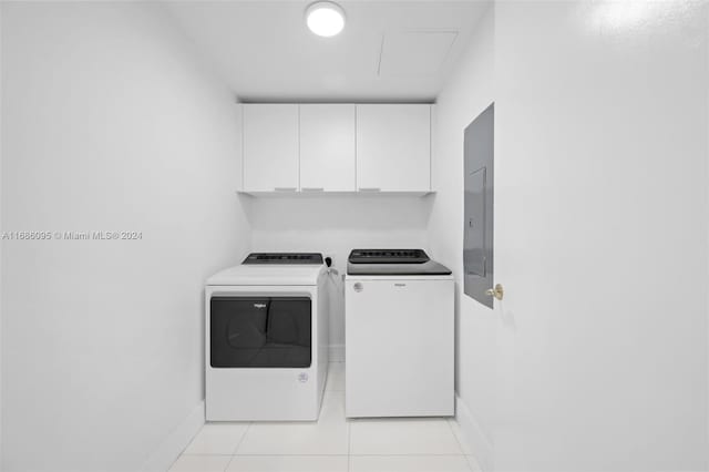 clothes washing area with light tile patterned flooring, electric panel, cabinets, and washer and dryer