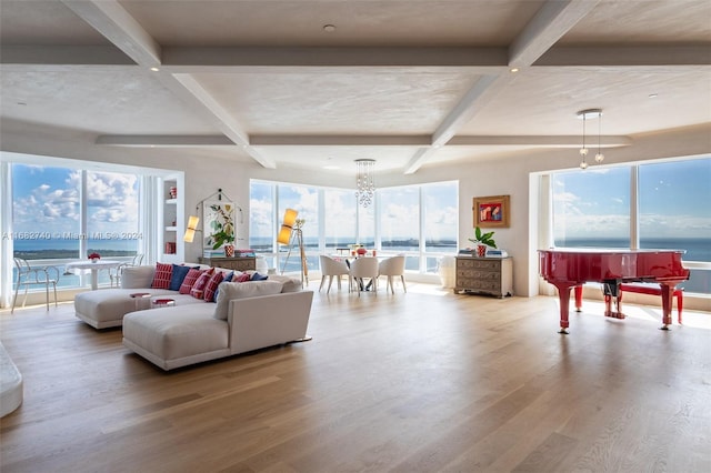 living room with an inviting chandelier, light hardwood / wood-style flooring, beamed ceiling, and a water view