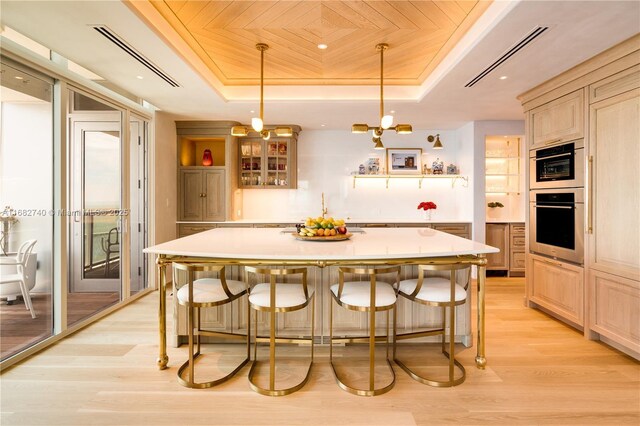 1425 Brickell Ave Unit 55F, Miami, FL 33131 - kitchen featuring a tray ceiling, light wood finished floors, light countertops, a kitchen bar, and wooden ceiling