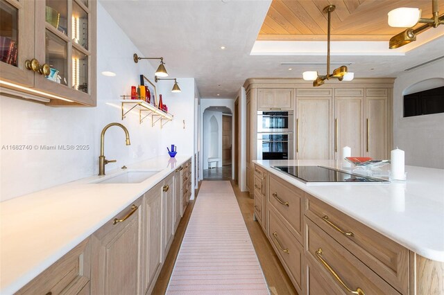 1425 Brickell Ave Unit 55F, Miami, FL 33131 - kitchen featuring a sink, double oven, black electric cooktop, arched walkways, and light countertops