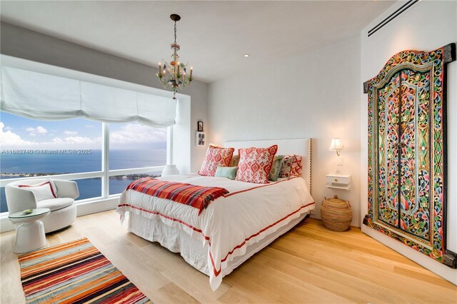 1425 Brickell Ave Unit 55F, Miami, FL 33131 - bedroom featuring wood finished floors, a chandelier, and a water view