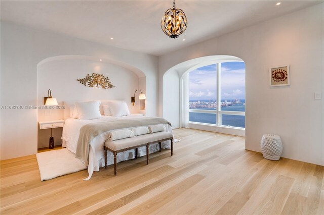 1425 Brickell Ave Unit 55F, Miami, FL 33131 - bedroom featuring wood finished floors, a chandelier, arched walkways, and recessed lighting