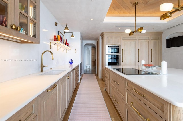 kitchen featuring hanging light fixtures, light hardwood / wood-style flooring, black electric stovetop, double oven, and sink