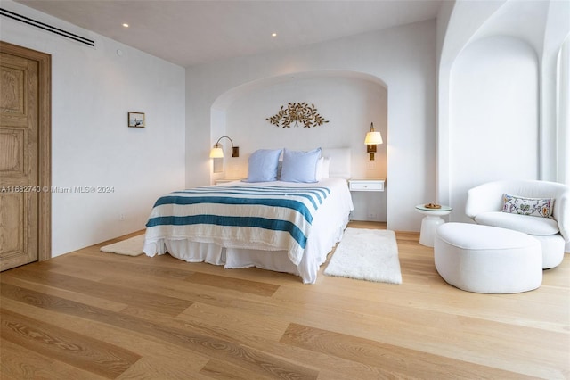 bedroom featuring a wall mounted AC and light hardwood / wood-style floors