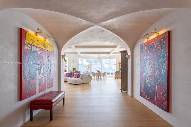 corridor with lofted ceiling, decorative columns, an inviting chandelier, and hardwood / wood-style floors