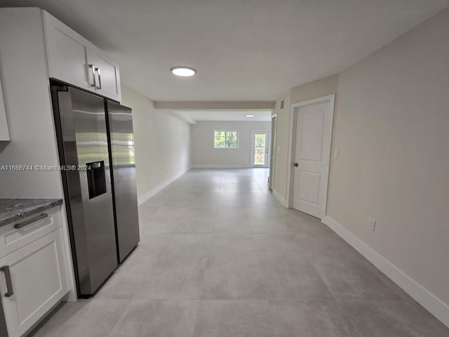 kitchen featuring white cabinets, dark stone countertops, and stainless steel fridge