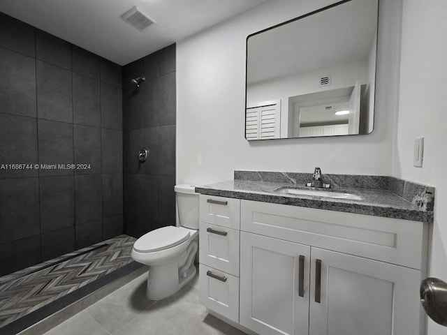 bathroom with vanity, toilet, tile patterned floors, and tiled shower