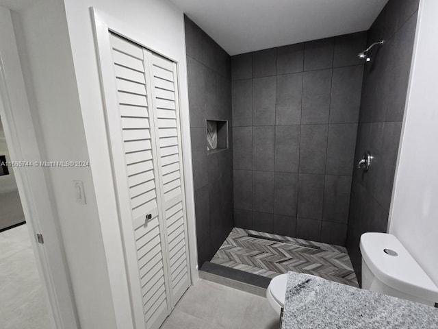 bathroom featuring a tile shower, toilet, and tile patterned flooring