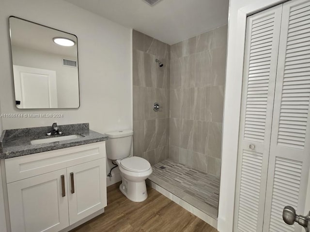 bathroom featuring vanity, toilet, tiled shower, and hardwood / wood-style floors