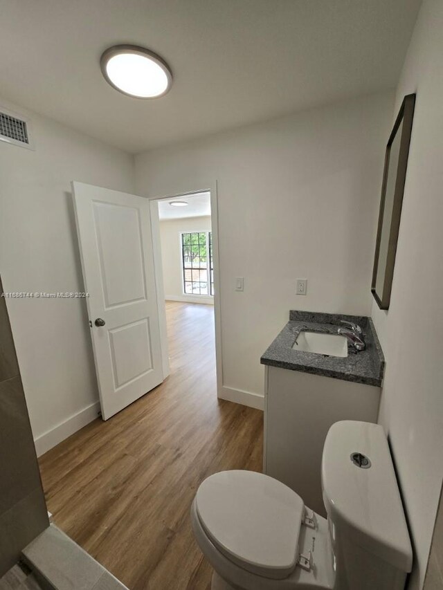 bathroom featuring vanity, wood-type flooring, and toilet