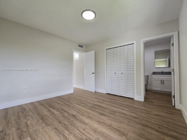 unfurnished bedroom featuring ensuite bathroom, sink, and wood-type flooring