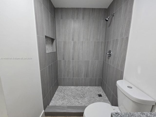 bathroom featuring tiled shower and toilet