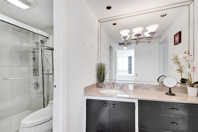 bathroom featuring a textured ceiling, an enclosed shower, toilet, vanity, and a notable chandelier