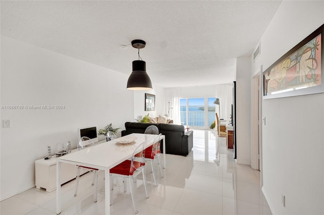 tiled dining space featuring a textured ceiling and a healthy amount of sunlight