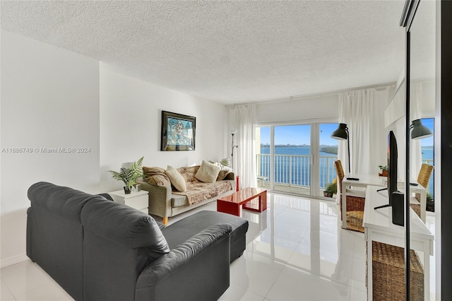 tiled living room featuring a textured ceiling and a water view