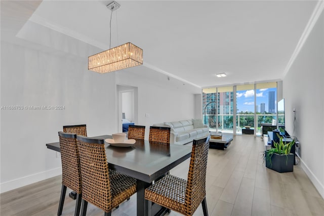 dining space with a notable chandelier, light hardwood / wood-style floors, crown molding, and a wall of windows