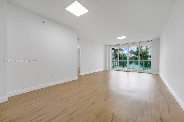 spare room with a wall of windows and light wood-type flooring