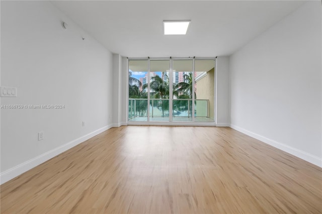 unfurnished room with expansive windows and light wood-type flooring