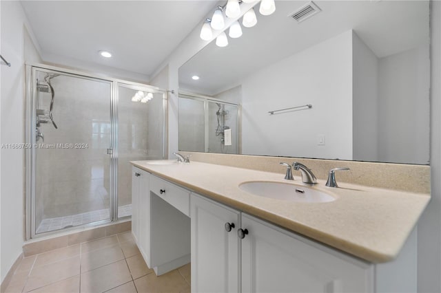 bathroom with a shower with door, vanity, and tile patterned floors