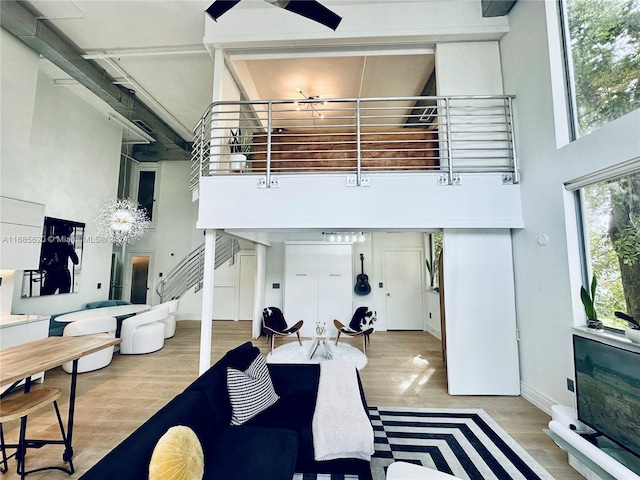 living room with a high ceiling, light wood-type flooring, and ceiling fan