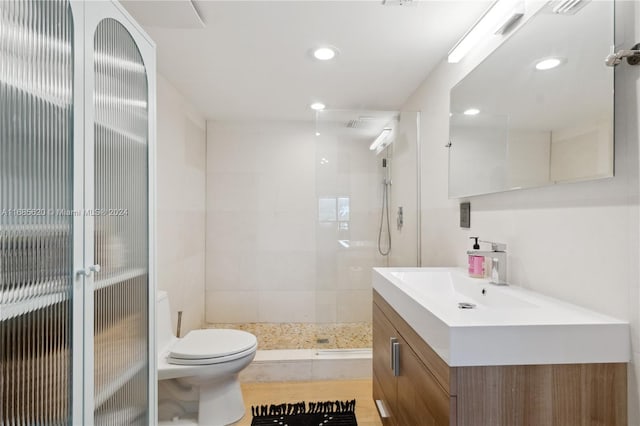 bathroom featuring vanity, toilet, and a tile shower