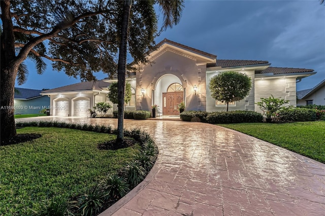 mediterranean / spanish home featuring a garage and a front lawn