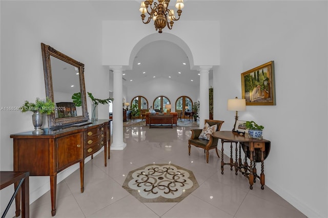 foyer featuring light tile patterned floors, ornate columns, a notable chandelier, and a high ceiling