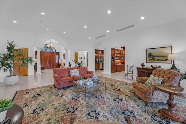 living room with decorative columns, a high ceiling, and a notable chandelier