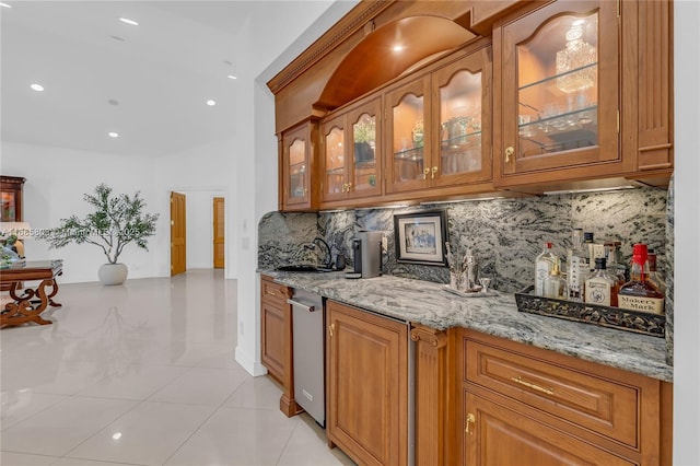 bar with decorative backsplash, light stone countertops, sink, and light tile patterned floors