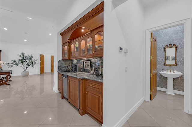 bar featuring tasteful backsplash, light stone countertops, sink, and light tile patterned flooring