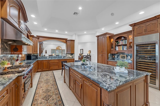 kitchen with a center island with sink, dark stone countertops, sink, and wine cooler