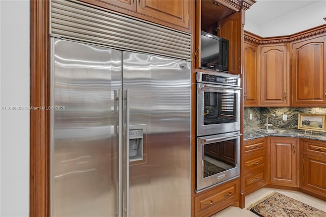 kitchen featuring light tile patterned floors, stainless steel appliances, tasteful backsplash, and dark stone countertops