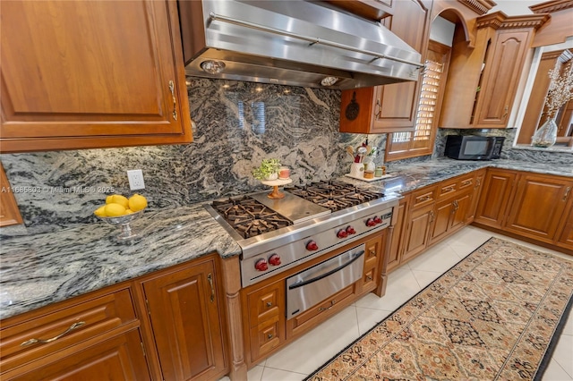 kitchen featuring light stone countertops, light tile patterned floors, backsplash, and extractor fan