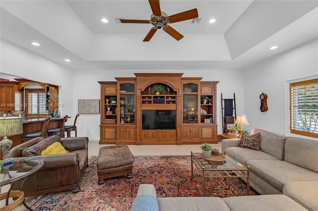 living room featuring ceiling fan, a raised ceiling, and a towering ceiling