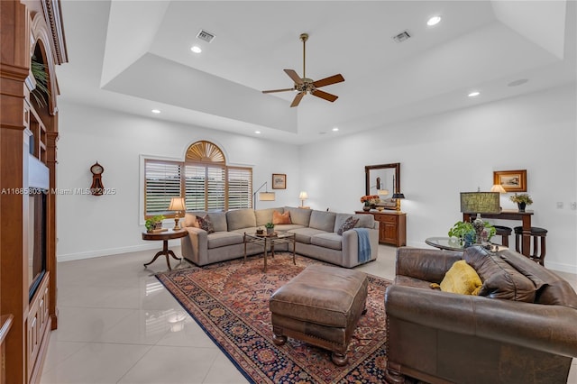 living room with light tile patterned floors, a towering ceiling, a raised ceiling, and ceiling fan