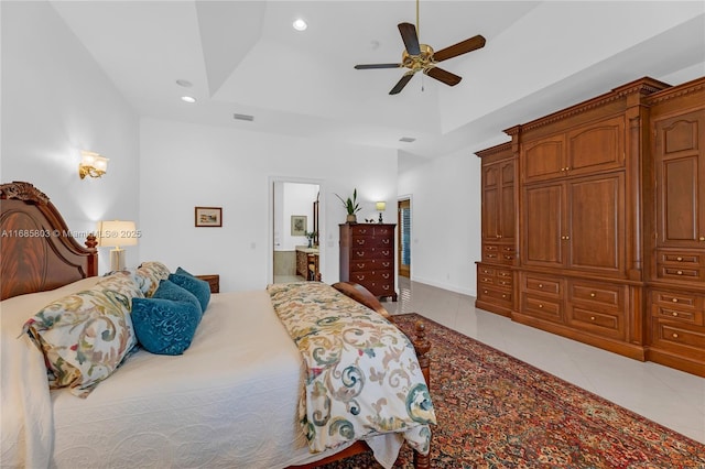 bedroom featuring light tile patterned floors, a tray ceiling, ensuite bath, and ceiling fan