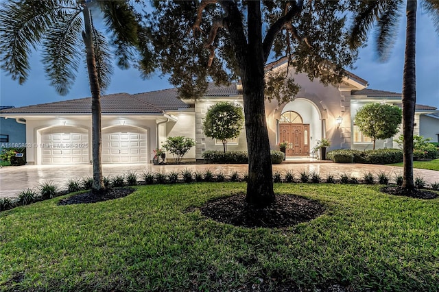 mediterranean / spanish-style home featuring a garage and a front yard