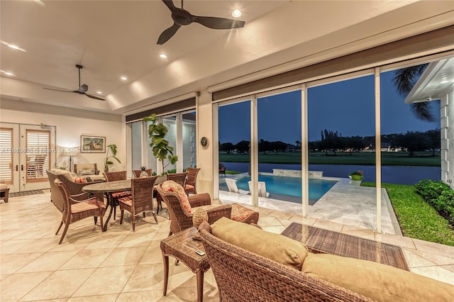 sunroom featuring ceiling fan and a water view