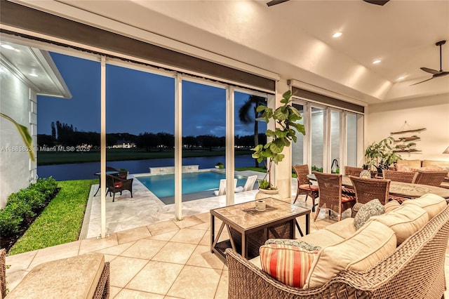 interior space with tile patterned floors, ceiling fan, a tray ceiling, and a water view