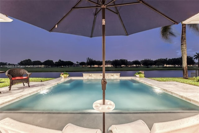 view of swimming pool featuring pool water feature, a water view, and a patio