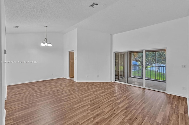 spare room with an inviting chandelier, a textured ceiling, high vaulted ceiling, and wood-type flooring