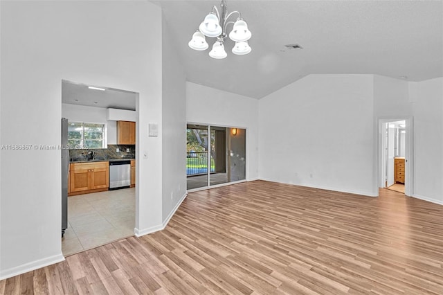 unfurnished living room with baseboards, light wood-style flooring, high vaulted ceiling, and a notable chandelier