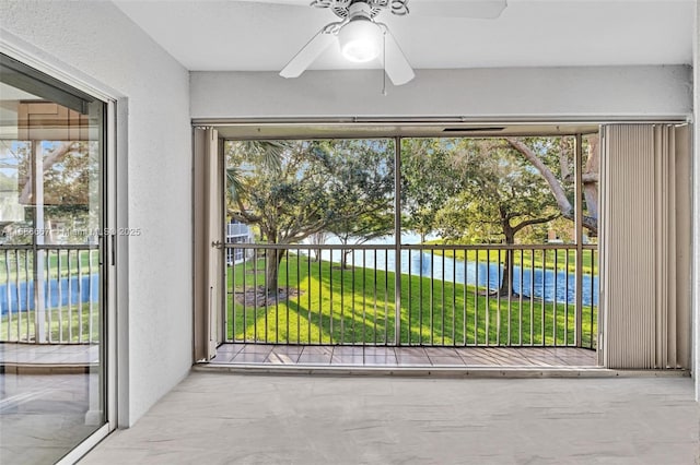 interior space featuring a ceiling fan, a water view, and a textured wall