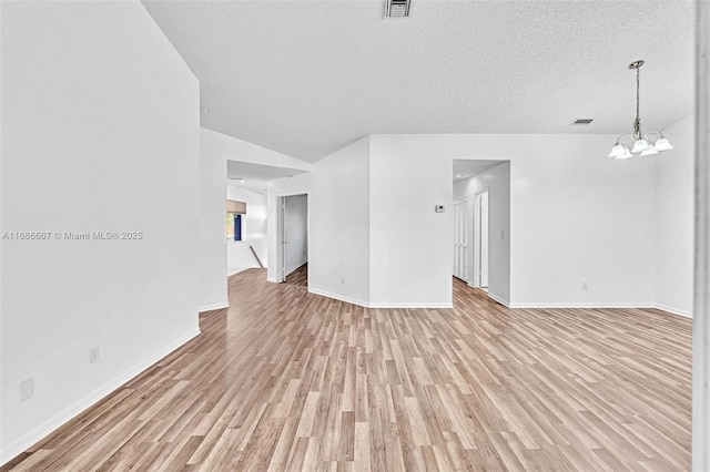 unfurnished living room featuring baseboards, visible vents, a textured ceiling, light wood-style floors, and a chandelier